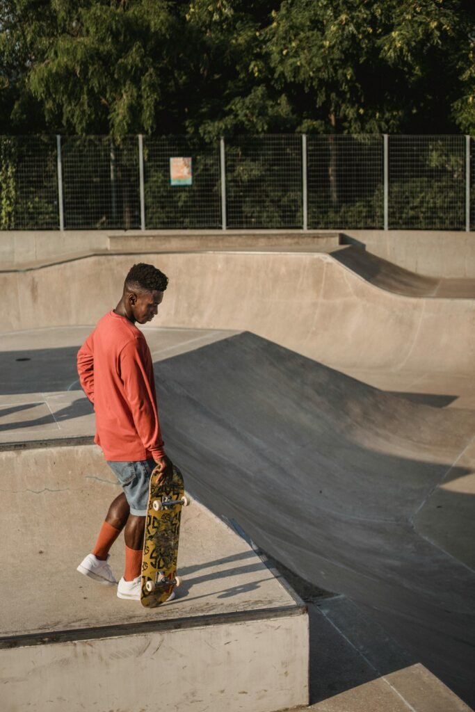 Skateboarder in urban skate park during a sunny day with trees in background.